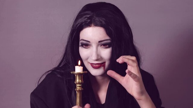 Young woman with halloween makeup making magic stuff with candle