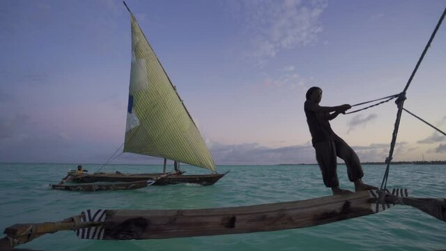 Outrigger sailing dhow travelling off the coast of Zanzibar. Tanzania. Africa.