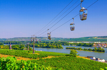 Cable car on rope of cableway from Rudesheim am Rhein town to Roseneck mount above vineyards fields of river Rhine Valley hills, blue clear sky background in sunny summer day, State of Hesse, Germany