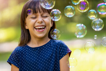 Girl playing with soap bubbles outdoors
