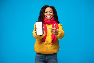 Black Woman Showing Cellphone Blank Screen Over Blue Studio Background