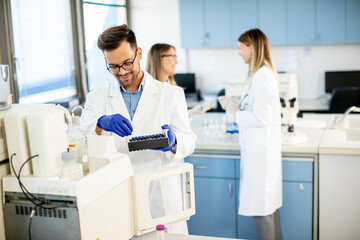 Fototapeta premium Researcher in protective workwear standing in the laboratory and analyzing liquid samples