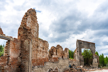 Fototapeta na wymiar Destroyed wall. Fragments of the wall against the sky. Ruins of houses. Summer day.