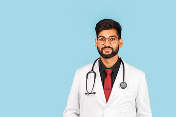 Cute Indian / Asian doctor wearing glasses with stethoscope, tie and white coat on light blue background.
