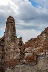 Destroyed wall. Fragments of the wall against the sky. Ruins of houses. Summer day.