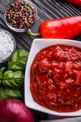 Fresh tasty tomato sauce on rustic wooden background