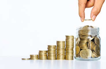 business man hand put coin on glass jar with many coins step growth up on white table against white background. money saving and owner investment concept for business financial.