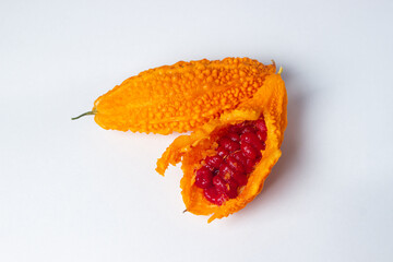Momordica on a white background. An exotic vegetable. Opened momordica, inside red seeds