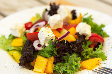 Greek salad on a white plate in a summer cafe. Vegetarian dish. Olives, purple onions and feta cheese. Light snack in a cafe. Summer menu. Natural light.