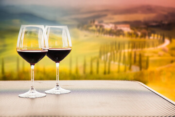 two glasses of red wine against beautiful landscape in Tuscany