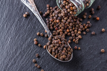 aromatic black pepper on a dark stone background