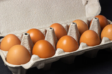 Eggs on a black background. Chicken eggs in a paper box