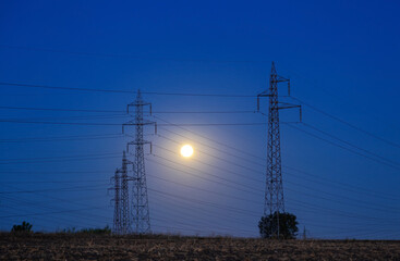 Full moon over a high voltage pylon