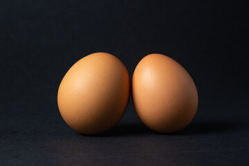 Eggs on a black background. Two chicken eggs next to each other.