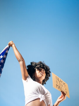 Black girl holding a US flag and a black lives matter sign