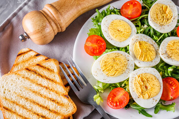 salad with boiled chicken eggs and cherry tomatoes on a stone background