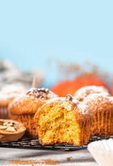 Freshly baked pumpkin muffins and walnuts, cinnamon and nutmeg on a blue background. Free space for...