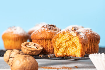 Freshly baked pumpkin muffins and walnuts, cinnamon and nutmeg on a blue background. Free space for text. Autumn or winter food. Sweet seasonal pumpkin baked goods. Copy space.