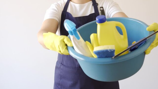Cleaning lady with gloves carries different cleaning products.