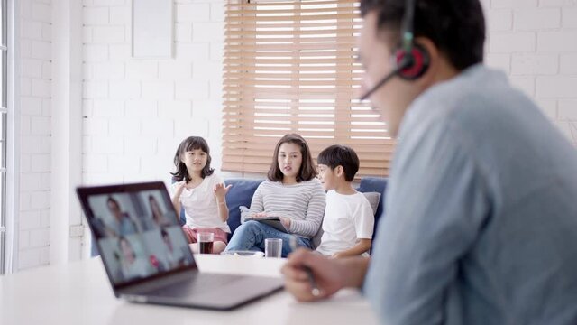 Medium shot : Asian business man stay with family and work remotely at home video conference remote call to corporate group. Meeting online,videocall, group discuss online concept.