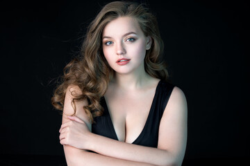 Naklejka premium Young beautiful woman with natural makeup on black background. Beauty & Skin care concept. Plus size model.