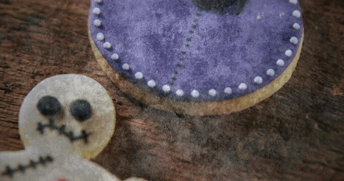 Scary gingerbread man and purple cheese cake against wooden surface