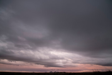Fototapeta na wymiar Dark storm clouds hanging over the black silhouette of the field