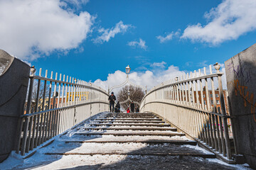 Ha' penny Bridge covered with snow. This pedestrian overpass is a popular historical landmark across River Liffey and connects Temple Bar with the North Inner City - Dublin, Ireland