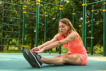 fitness woman is doing sport exercises on a workout area in a Park.