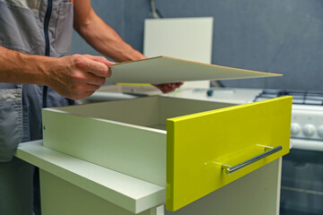 worker is assembling kitchen cabinet. refurbishment in the apartment. assembly of furniture in the house. kitchen assembling close up. 