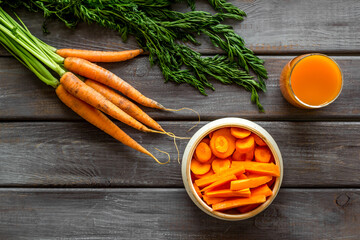 Carrot slices, fresh juice, vegetable with green tops top view copy space