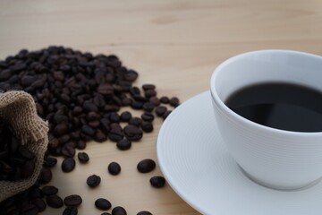 cup of coffee with beans on wooden table background 
