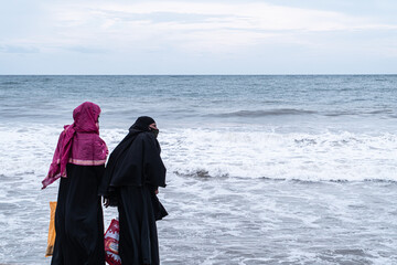 Kobiety, muzułmanki w burkach nad brzegiem oceanu.