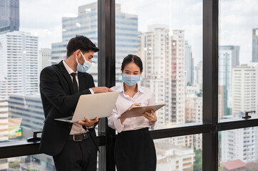Multi ethnic business colleague wearing face mask discussing and consulting in new normal office at business district
