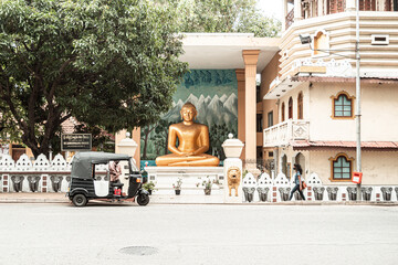 A golden statue of Buddha against the background of the stupa and the temple.