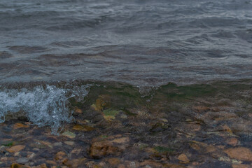 bright gray green waves of lake baikal, pebbles, stones in water, coast summer