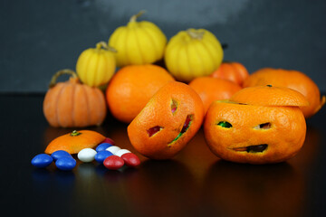 Halloween concept. Funny orange mandarins or tangerines pumpkin carved in the form of icons of Halloween on a black background. Alternatives to traditional Halloween pumpkins. Creative autumn composit