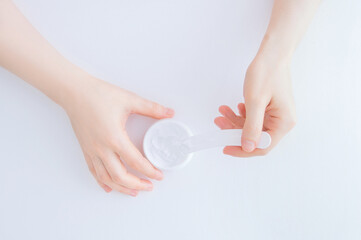 A jar of face cream on the table in hand of a Caucasian woman. white  background.