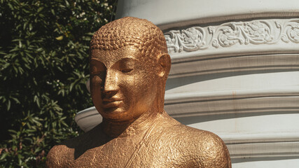 A golden statue of Buddha against the background of the stupa and the temple. © insomniafoto