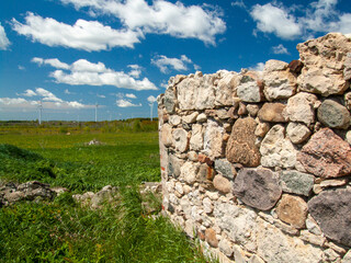 old stone wall with blue sky and wind turbines in background