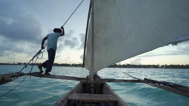 Outrigger sailing dhow travelling off the coast of Zanzibar. Tanzania. Africa.
