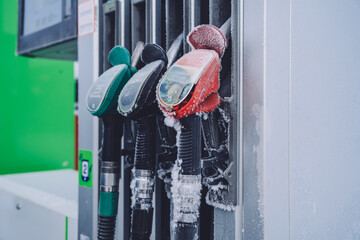 Cropped image of frozen cold tanker with nozzles for refill for automobile in winter, gas station...