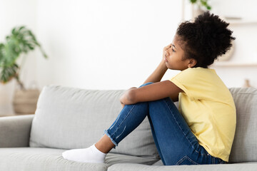 Unhappy Black Kid Girl Sitting On Couch At Home Alone