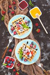Tasty waffles with fresh berries and whipped cream on black background