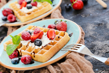 Tasty waffles with fresh berries and whipped cream on black background