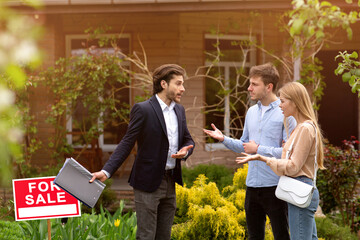 Real estate broker arguing with upset clients in front of country house outdoors