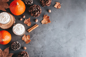 Autumn border with natural pine cones, pumpkins, dried leaves and pumpkin latte on dark grey stone...