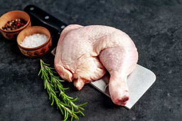 raw chicken quarters with spices over a meat knife on a stone background