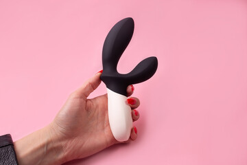 Dildo in hand on a pink background, sex toy