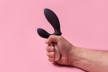 Dildo in hand on a pink background, sex toy